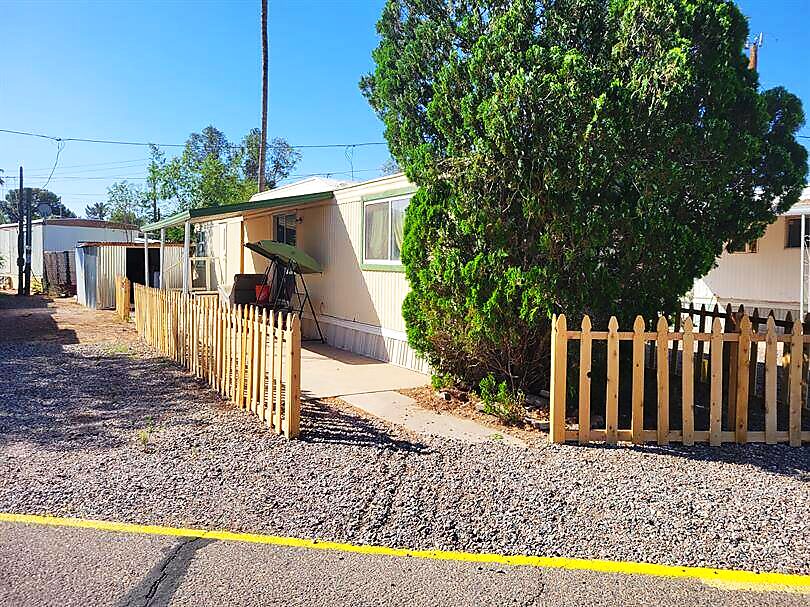 Manufactured home with picket fence and shade tree